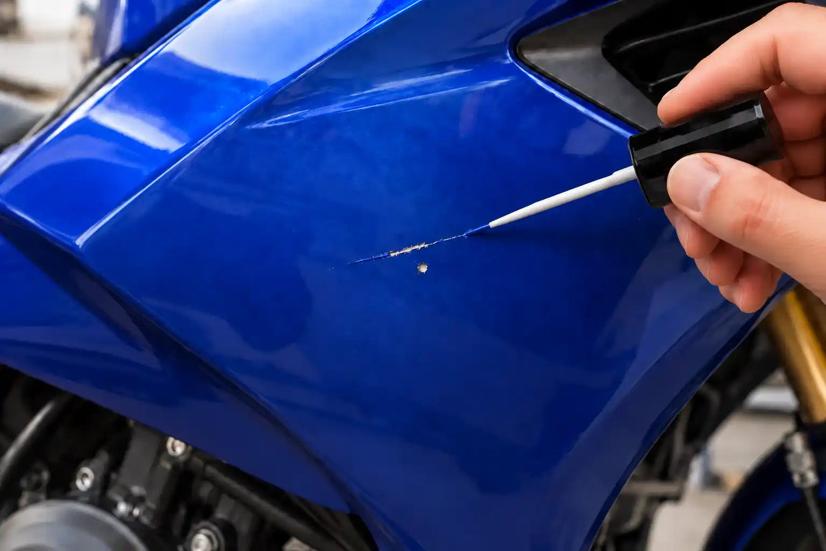 Application de peinture sur un carénage moto bleu avec le pinceau intégré au bouchon